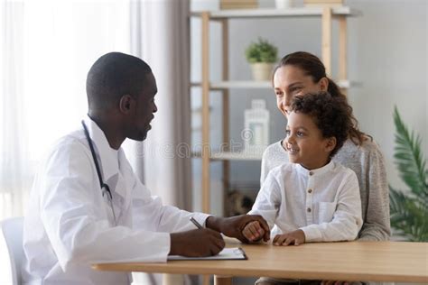 Smiling Mom With Little Son Visiting African American Doctor Stock