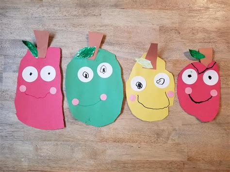 Four Different Colored Paper Bags With Faces And Eyes Hanging From Them