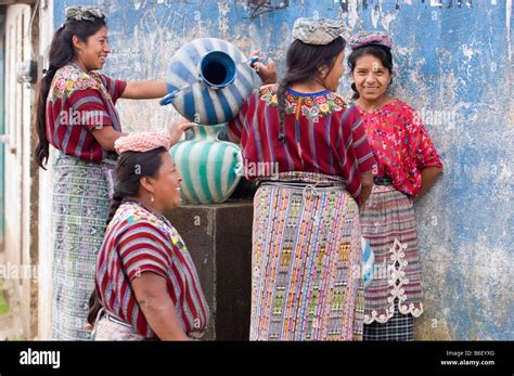Las mujeres indígenas en el colorido traje recogiendo agua en la