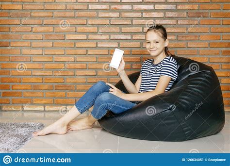 Smiling Caucasian Teen Girl Sitting In Black Bean Bag