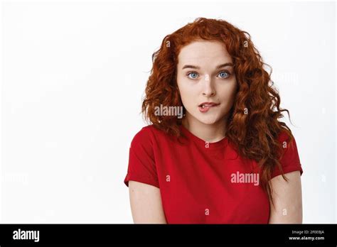 Portrait Of Silly Redhead Girl Acting Innocent And Shy Biting Lip And Looking Cute At Camera