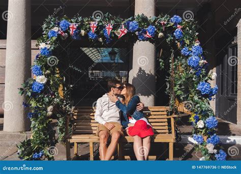 Couple In Love Kissing Seated On A Swinging Bench In Covent Garden