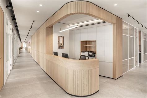 An Office With Curved Wooden Desk And White Walls