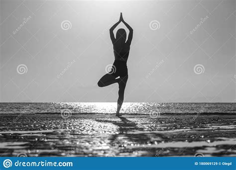 Silhouette Of Woman Standing At Yoga Pose On The Tropical Beach During