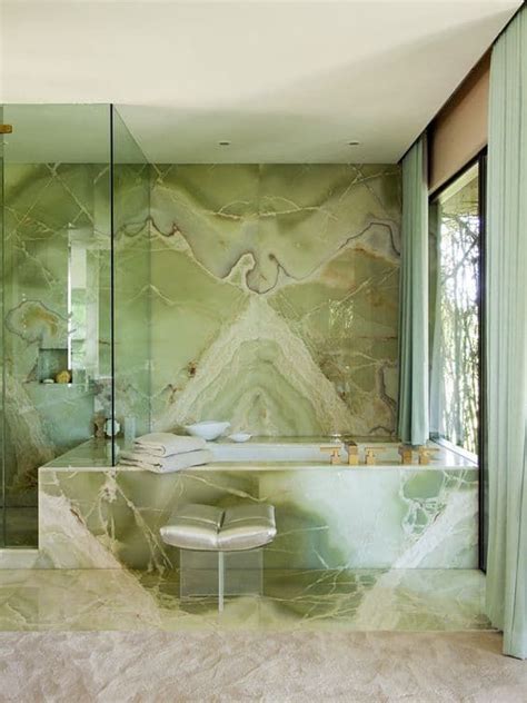 A Bathroom With Green Marble Walls And Flooring Along With A Large Bathtub
