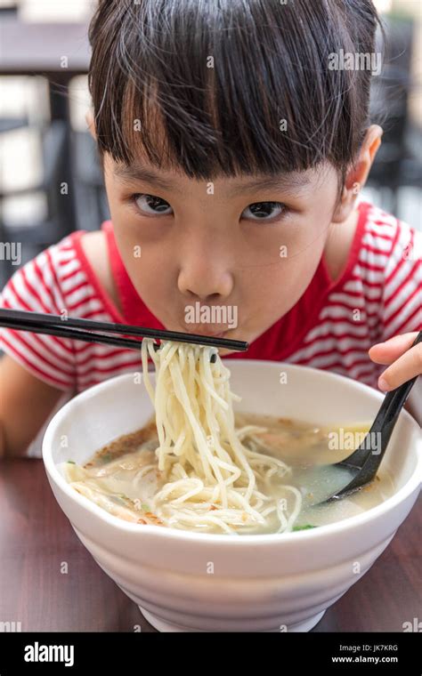 Asian Little Chinese Girl Eating Noodles Soup In Outdoor Cafe Stock