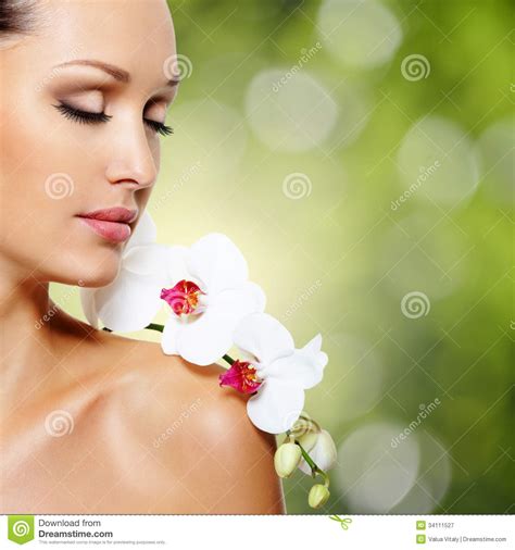 Face Of Beautiful Woman With A White Orchid Flower Stock