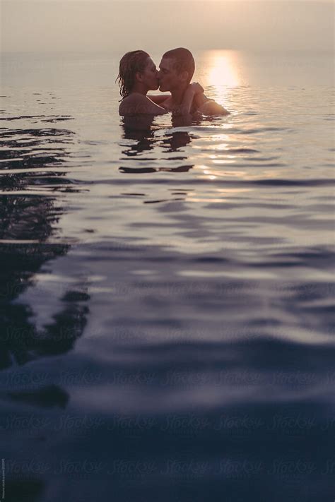 Couple Kissing In The Pool At Sunset By Stocksy Contributor Mosuno Stocksy