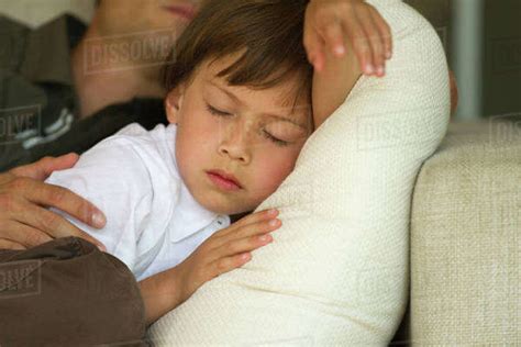 Boy Napping On Sofa With His Father Cropped Stock Photo Dissolve