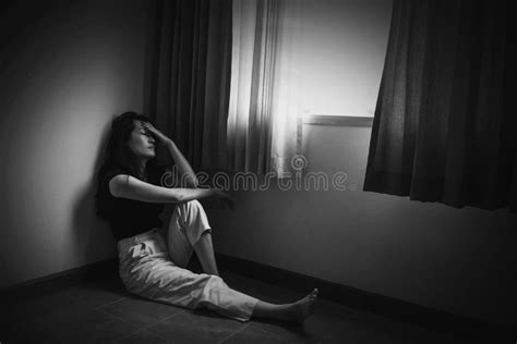 Depress Woman Sitting On Floor In Room Near Window In White Tone Stock