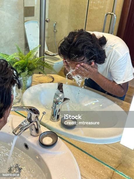Closeup Image Reflection In Mirror Of Indian Man Bent Over Sink Full Of