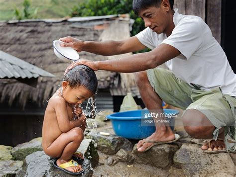 Man Bathing His Son With A Bucket In The Open Air Photo Dactualité