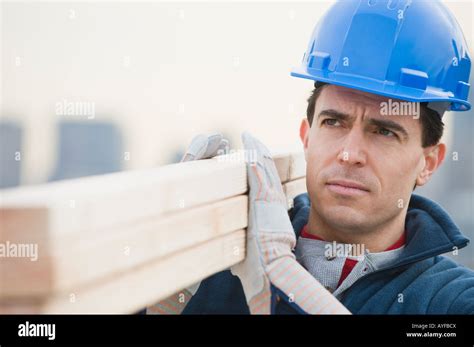 Male Construction Worker Holding Stack Of Lumber Stock Photo Alamy