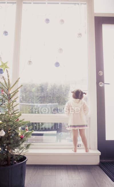 Curious Girl On Window Ledge Below Christmas Ornaments — 2 3 Years One