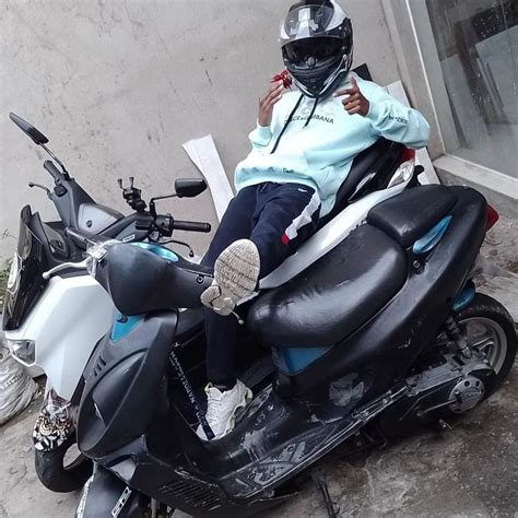 A Person Sitting On Top Of A Motor Scooter In Front Of A Building