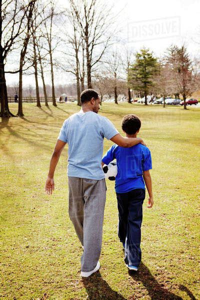 Father With Arm Around Son 10 11 Walking In Park Stock Photo Dissolve