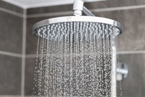 Close Up Of Water Streaming From Rain Shower Head In Bathroom Stock