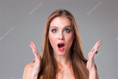 close up portrait of surprised beautiful girl holding her head in amazement and open mouthed