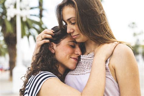 Two Female Friends Embracing And Hugging Outdoors Stock Photo