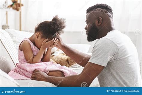 African Father Comforting Little Crying Girl At Home Stock Photo