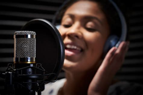 Female Vocalist Wearing Headphones Singing Into Microphone In Recording