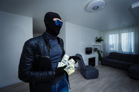 Robber Man Dressed In Black Hoodie Stands With Disguised Face And Holds