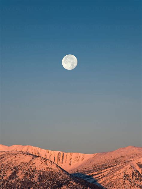 Full Moon Above The Sunrise Snow Mountain Peaks Del Colaborador De
