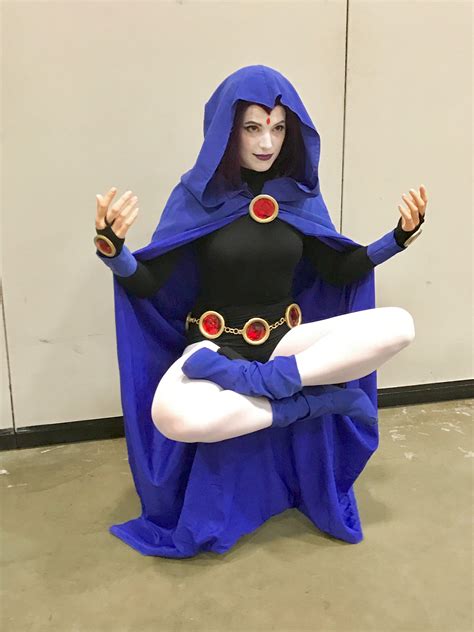 A Woman Dressed In Blue And Black Is Holding Her Arms Out While Sitting On The Floor