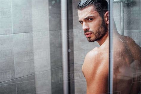 Handsome Man Looking At Camera While Taking Shower In Bathroom Stock