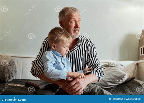 Grandfather And Grandson Using Digital Tablet While Sitting On Couch
