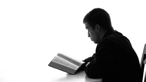 Silhouette Of A Young Man Reading The Bible And Praying Daily