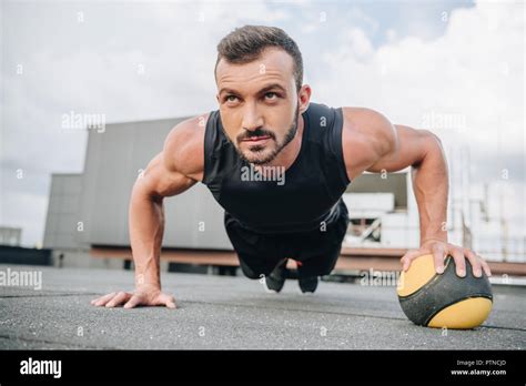 Handsome Muscular Sportsman Doing Push Ups With Medicine Ball On Roof