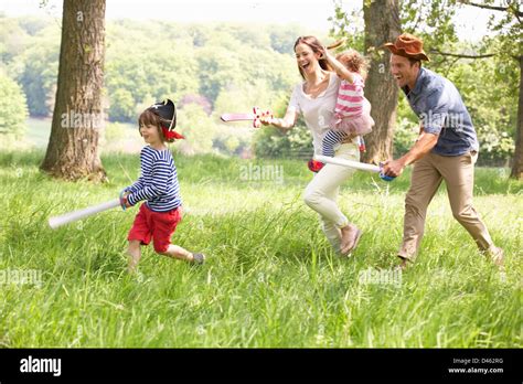 Parents Playing Exciting Adventure Game With Children In Summer Field