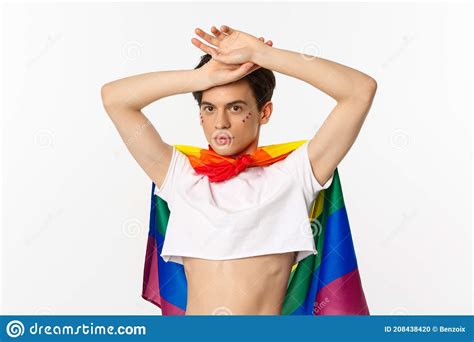Beautiful Gay Man With Glitter On Face Wearing Crop Top And Rainbow Lgbt Flag Posing Against