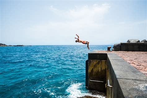Premium Photo One Young Man Jumping Off A Cliff Doing A Backflip To The Water Alone Fitness