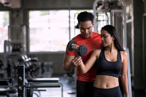 Personal Trainer Coach Dumbbell Exercise To Woman In Gym Stock Image