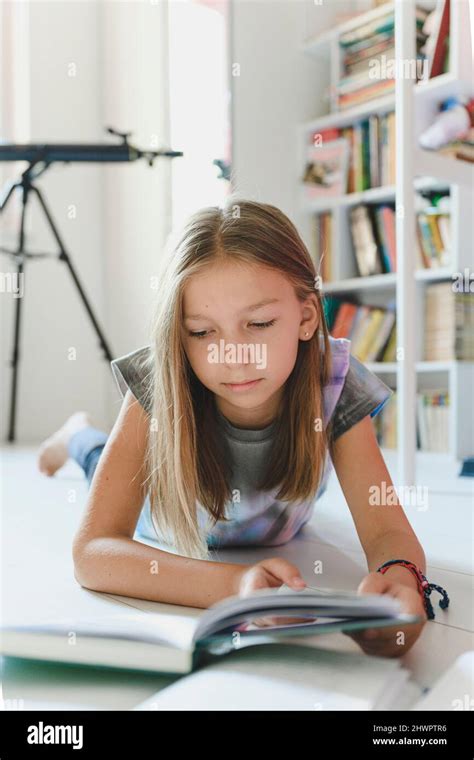 Girl Reading Book Lying At Home Stock Photo Alamy