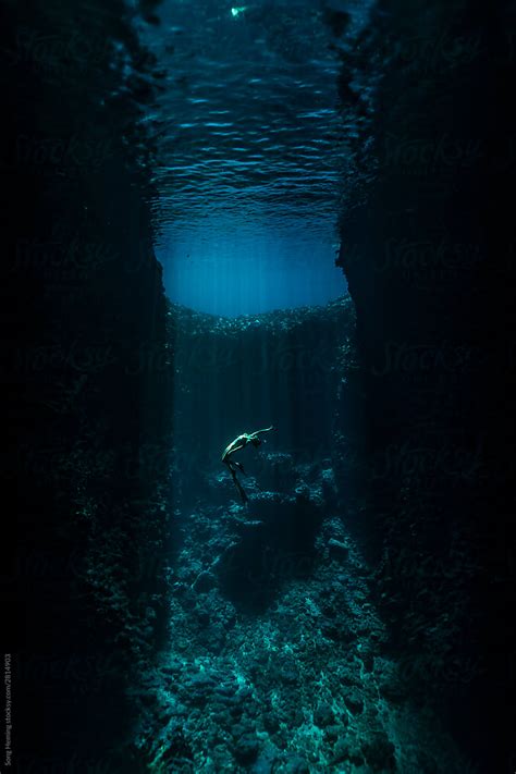 A Female Freediver With Bikini And Fins Diving In The Cave With Sun