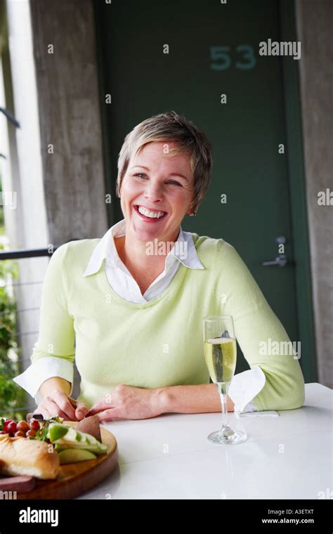 Portrait Of A Mature Woman Sitting At The Table And Smiling Stock Photo