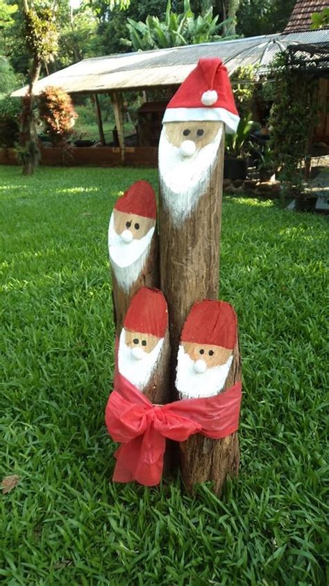 Three Wooden Santas Are Sitting On The Grass In Front Of A Tree Stump