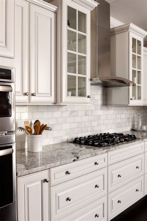 White glass front kitchen cabinets. Marble tile with white glass-front cabinets flanking a ...