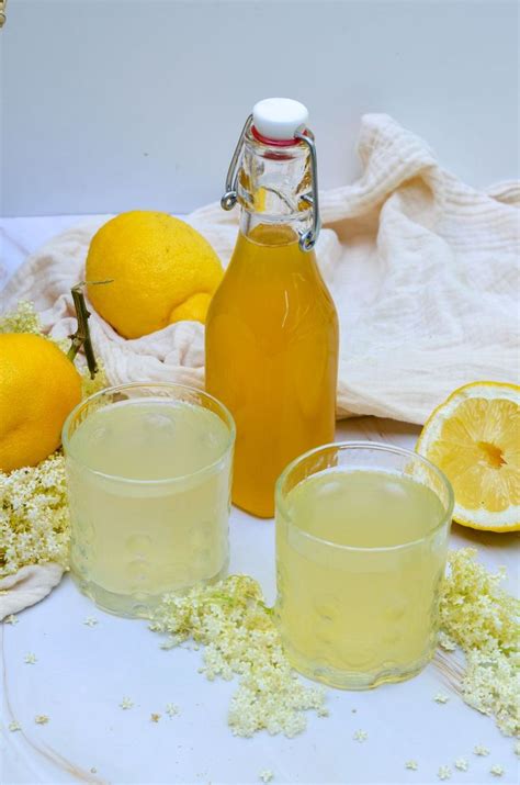 Two Glasses And A Bottle Of Lemonade On A White Plate With Some Yellow Flowers