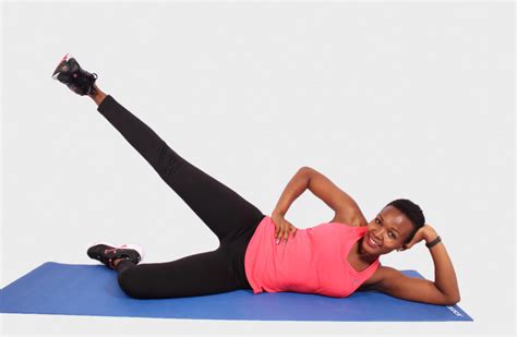 Smiling Woman On Yoga Mat Doing Side Lying Leg Raises
