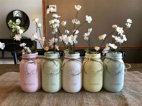 Four Painted Mason Jars With Flowers In Them