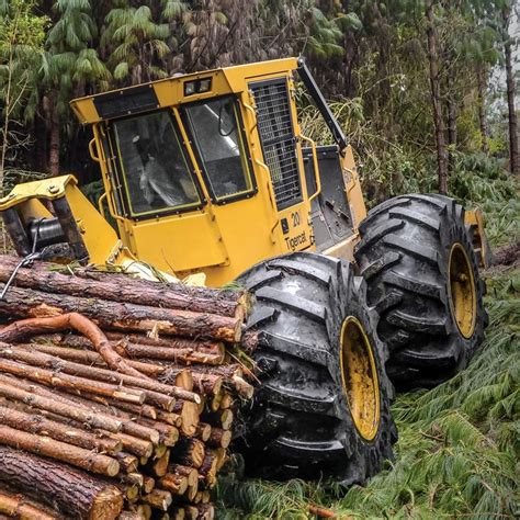 A Tractor Is Parked Next To Logs In The Woods