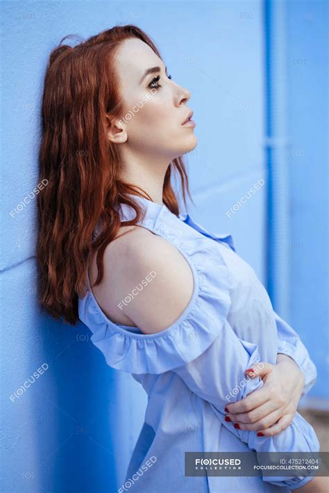 Redheaded Woman Leaning On Blue Wall Long Hair Casual Stock Photo