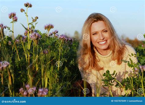 Attractive Middle Age Woman Sitting In A Lilac Flower Field Stock Image