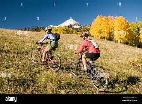 Two Women Mountain Biking Through Yellow Aspen Trees San Juan National