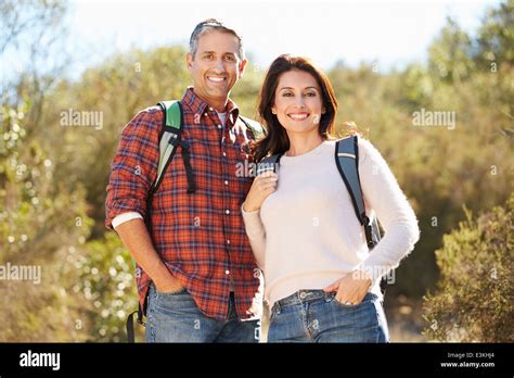 Portrait Of Couple Hiking In Countryside Wearing Backpacks Stock Photo