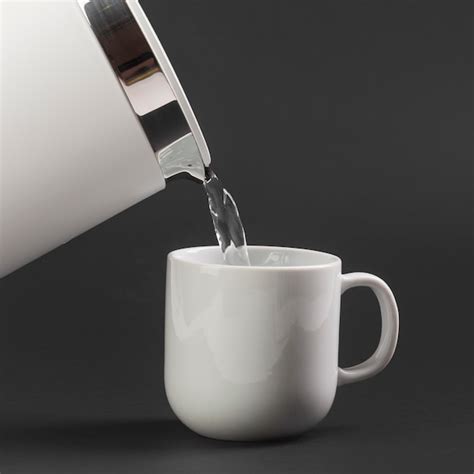 Free Photo Side View Electric Kettle Pouring Water In Cup